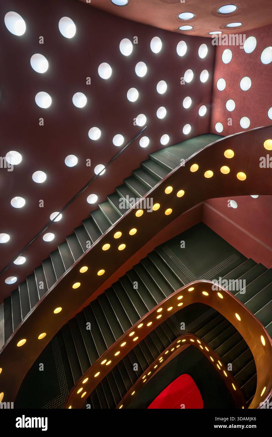 Blick auf eine Wendeltreppe mit runden Lichtern an den Wänden, die einen Polka Dot-Effekt erzeugen, der zu einer roten Landung führt, im Za Koenji Theatre, Tokio, Japan. Stockfoto