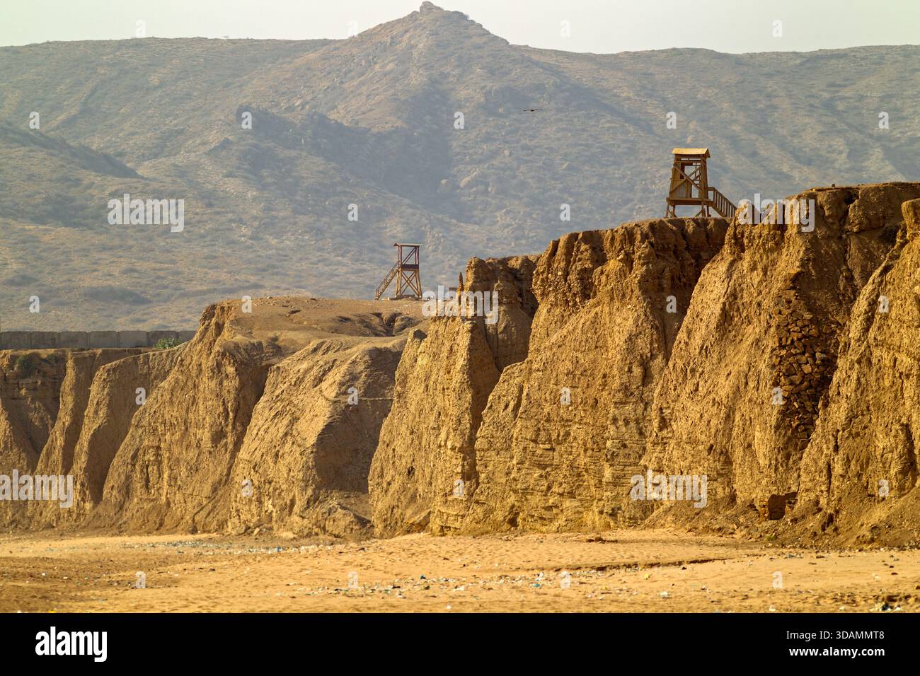 Der Blick auf goldene Klippen erhebt sich stark gegen die Skyline, gekrönt von hölzernen Aussichtspunkten, während Berge in der Ferne aufragen, Karachi, Sindh, Pakistan. Stockfoto