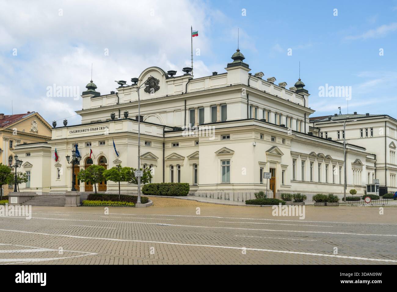Blick auf das große Gebäude der Nationalversammlung steht in reinem weiß vor dem hellen Himmel, Fahnen flattern, ein Zeugnis der Geschichte, Sofia City P Stockfoto