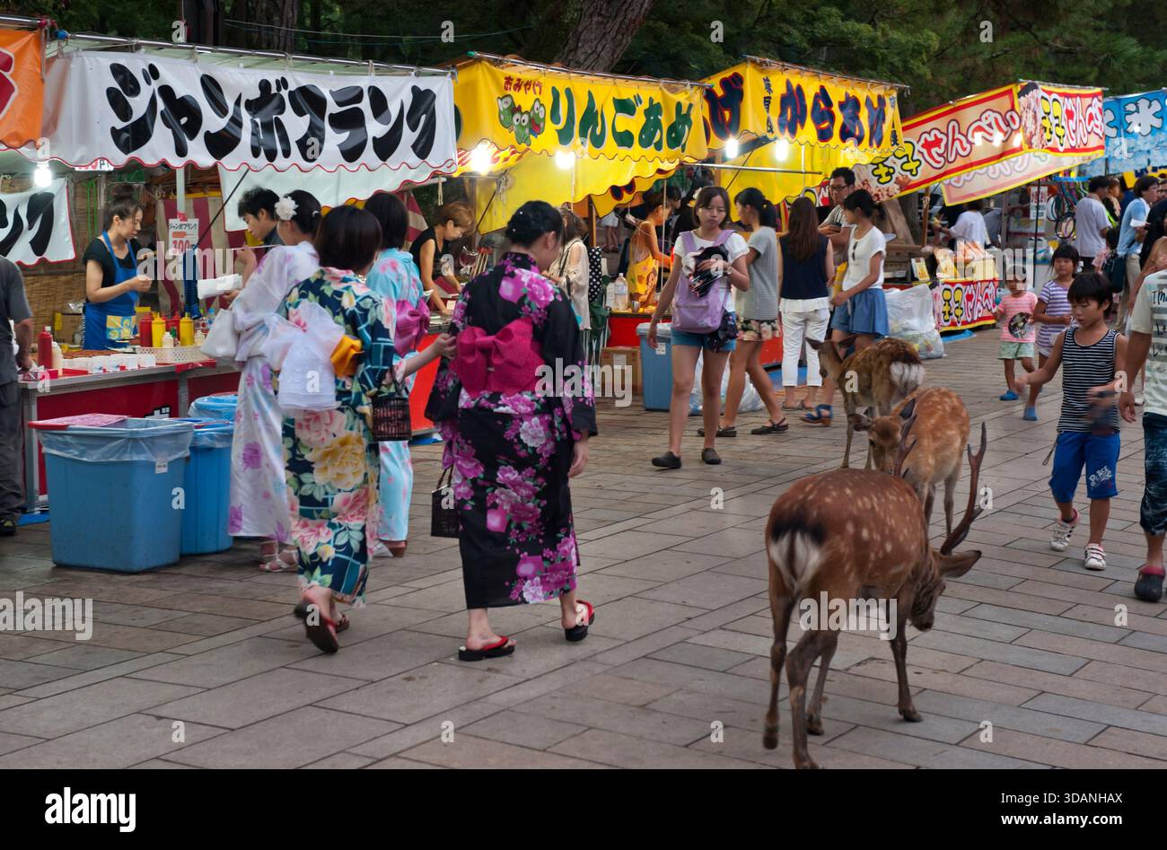 Besucher von Todaiji während der Obon-Festivalsaison in farbenfrohen Sommer-Yukata-Baumwoll-Kimono-Bademänteln und Snacks von den roten Boots in Nara, Japan. Stockfoto