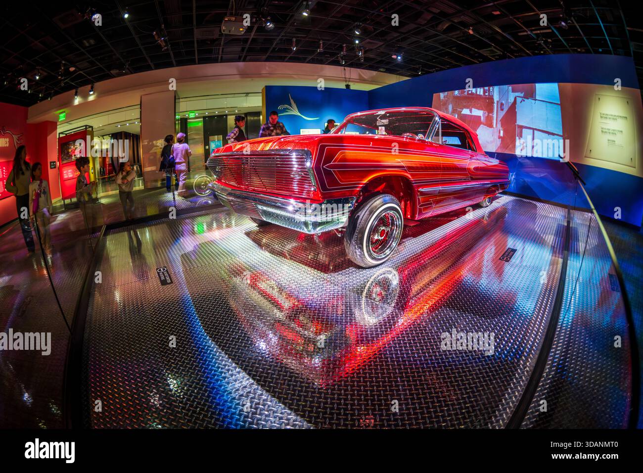 Smithsonian American History Museum Lowrider Culture Exhibit Washington DC // WASHINGTON DC — der Custom 1963 Chevy Impala 'El Rey' Lowrider ist in der Lowrider Culture Exhibit im Smithsonian American History Museum zu sehen. Der 2011 fertiggestellte, bonbonrote Wagen wurde über sechs Jahre von drei Generationen der Familie de Alba und anderen Mitarbeitern gebaut. Das Auto wurde zu Ehren von Albert de Albas Schwiegervater und seinem Lieblingslied von Vicente Fernández „El Rey“ genannt und zeigt ein individuelles digitales Armaturenbrett, geätzte Chromdetails und familieninspirierte Wandbilder. Es ist eine Leihgabe von Albert de Alba. Stockfoto