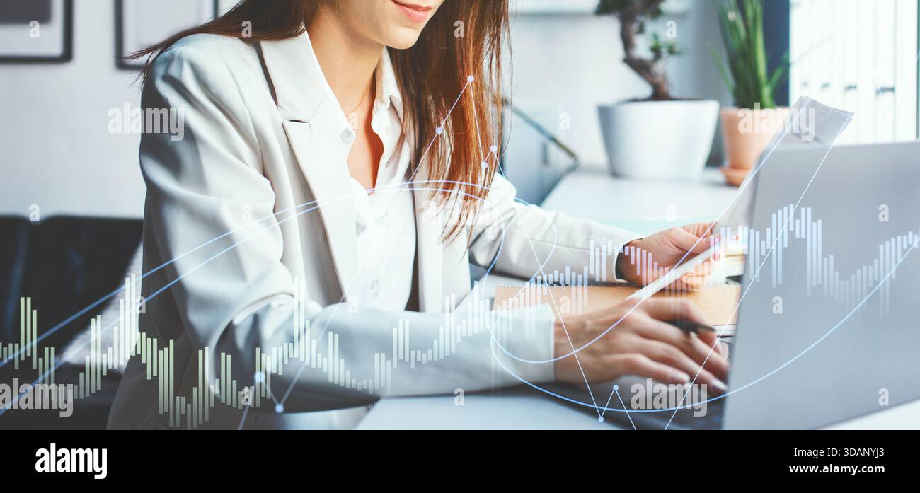 Positive Geschäftsfrau arbeitet während der Tageslichtstunden effektiv an ihrem modernen Schreibtisch Stockfoto