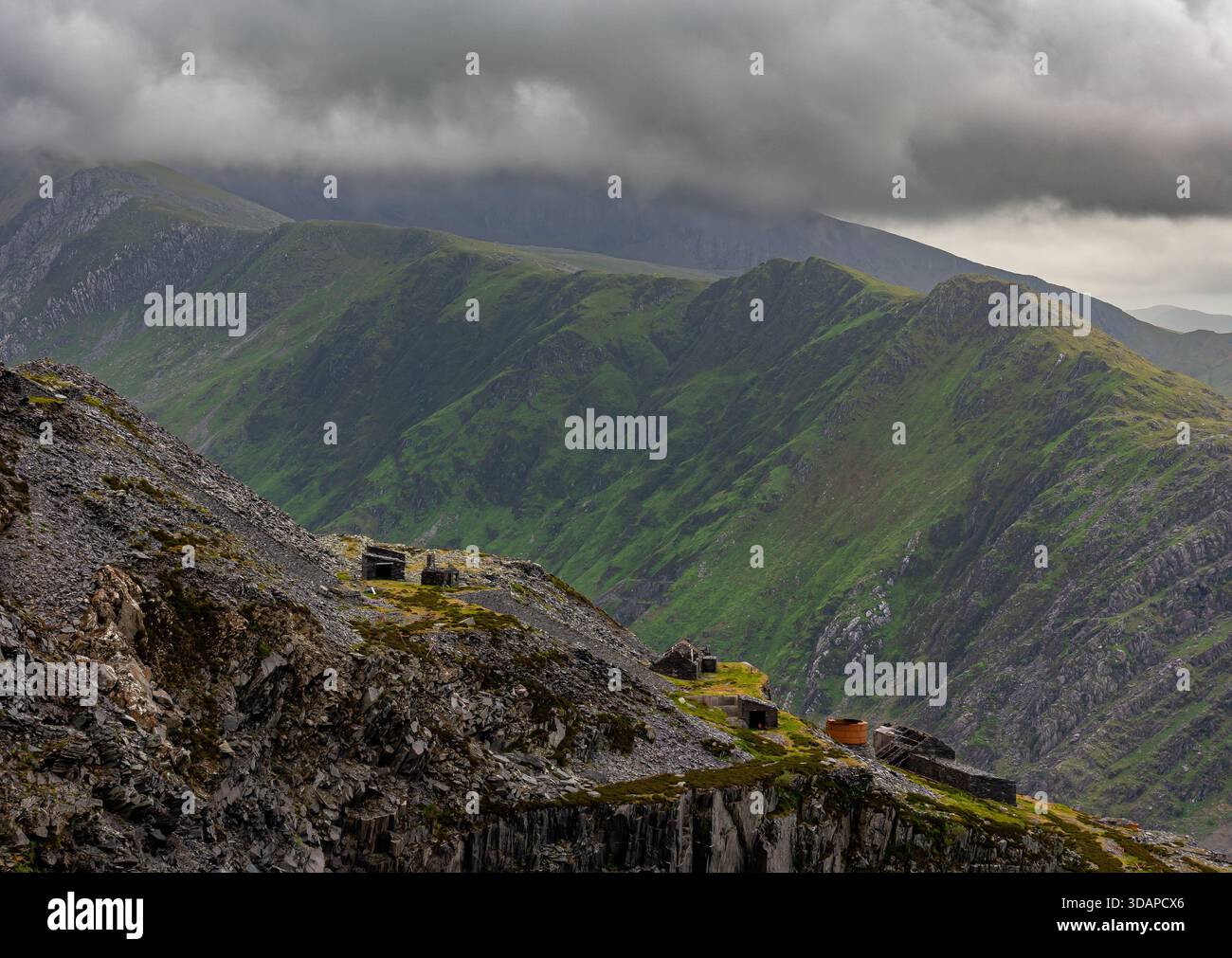 Verlassene Steinbruchgebäude und Schieferarbeiten in Dinorwic liegen hoch über steilen Berghängen unter schwerer Wolke Stockfoto