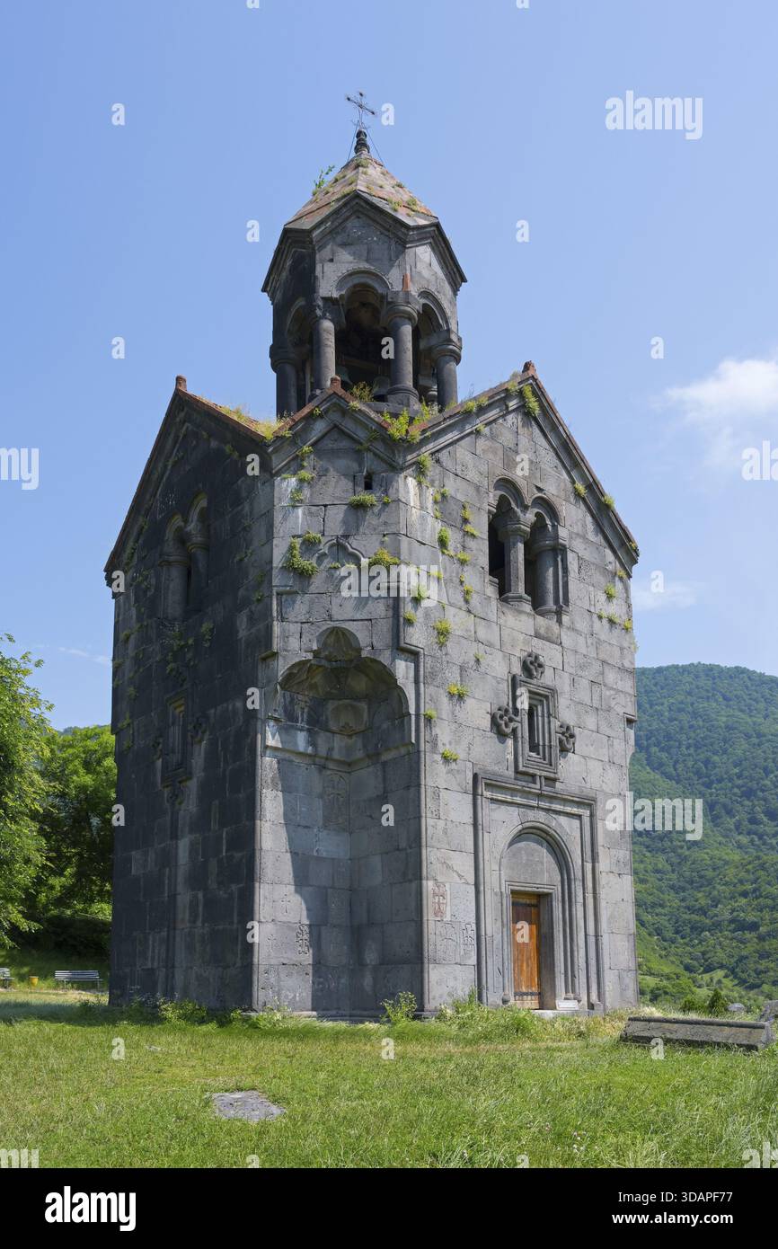Kleine Steinkirche mit Glockenturm, umgeben von grüner Natur und hohen Bergen im Hintergrund, Haghpat Kloster, Haghpatavank, Stadt von Stockfoto
