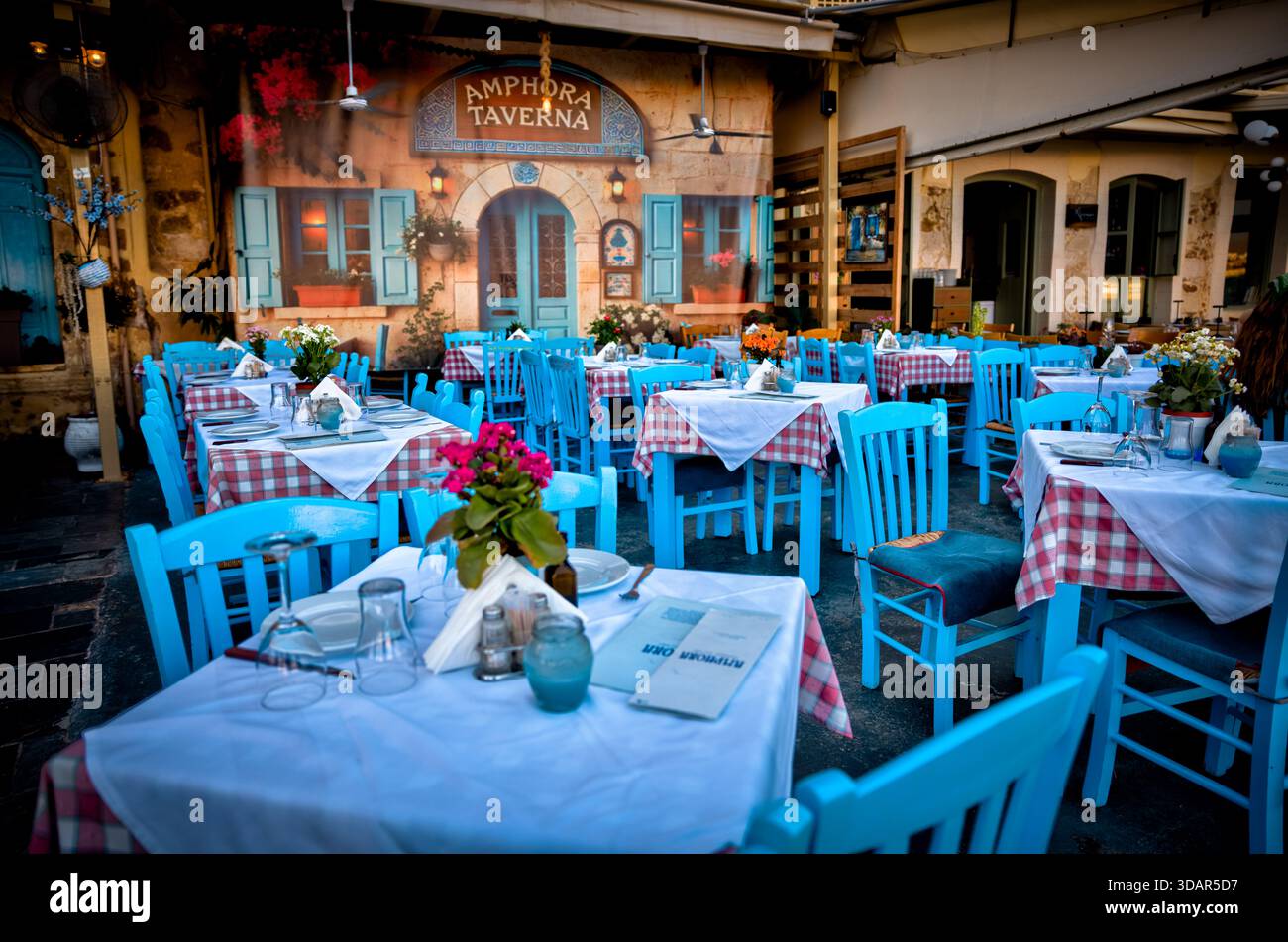 Esstische im Freien in der Taverna Amphora in der Altstadt von Chania, Kreta, Griechenland, mit traditioneller Einrichtung und abendlicher Atmosphäre. Stockfoto