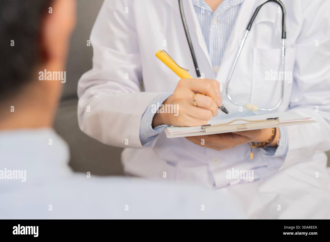 Abgeschnittene Aufnahme einer Ärztin in der Arztpraxis im Krankenhaus, mit Untersuchungsergebnissen auf Clipborad und Beratung mit Mann Patient Stockfoto