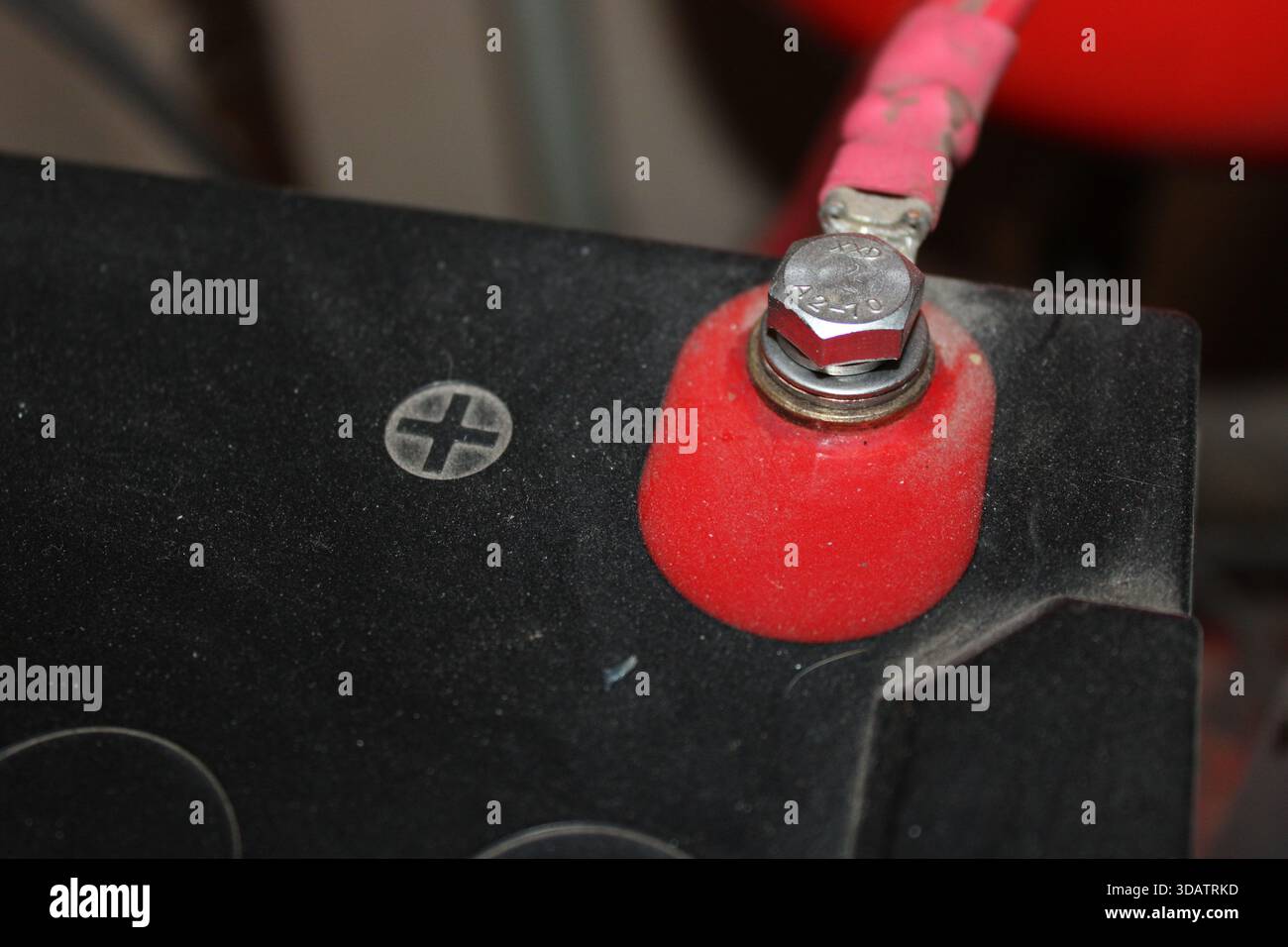 Eine Nahansicht zeigt eine rote Batteriepole, die an einer Batterie befestigt ist. Die Klemme verfügt über eine Mutter und eine Schraube, mit der sie befestigt ist. Der Schwerpunkt liegt auf der positiven Seite Stockfoto