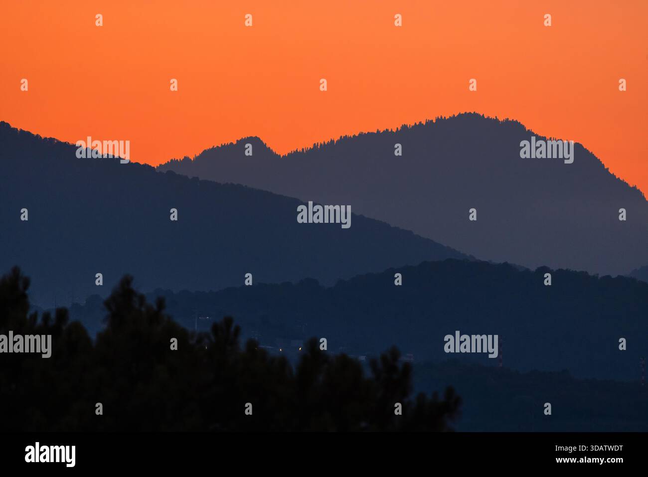 Goldener Sonnenaufgang über nebeligen Bergschichten schafft eine friedliche Landschaft im warmen Morgenlicht. Stockfoto