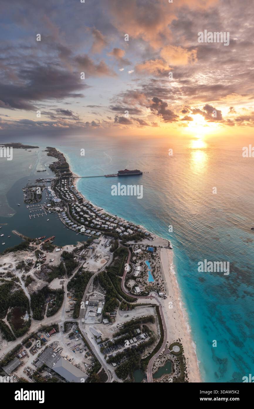 Aus der Vogelperspektive auf die Küste, wo das türkisfarbene Meer auf den Sandstrand unter einem dramatischen Sonnenuntergang trifft, Great Harbour Cay, Berry Islands, Bahama Stockfoto