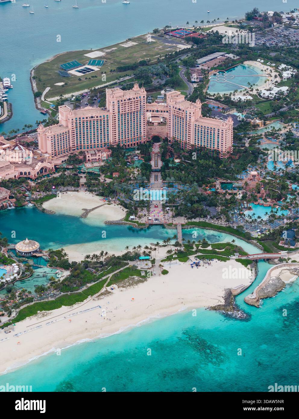 Majestätisch erhebt sich der Blick aus der Vogelperspektive auf das Grand Hotel, dessen pinkfarbene Fassade im Kontrast zum türkisfarbenen Meer und dem weißen Sandstrand, Great Harbour Cay, Berr, steht Stockfoto