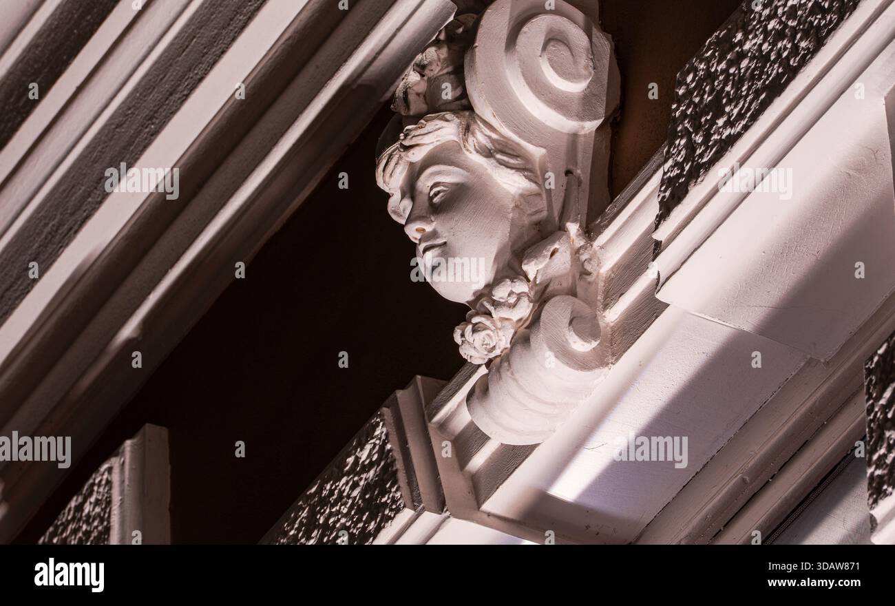 Nahaufnahme eines klassisch geformten Gesichts an einer historischen Gebäudefassade in Tiflis, Georgien. Wunderschöne dekorative Details in sanftem Abendlicht Stockfoto