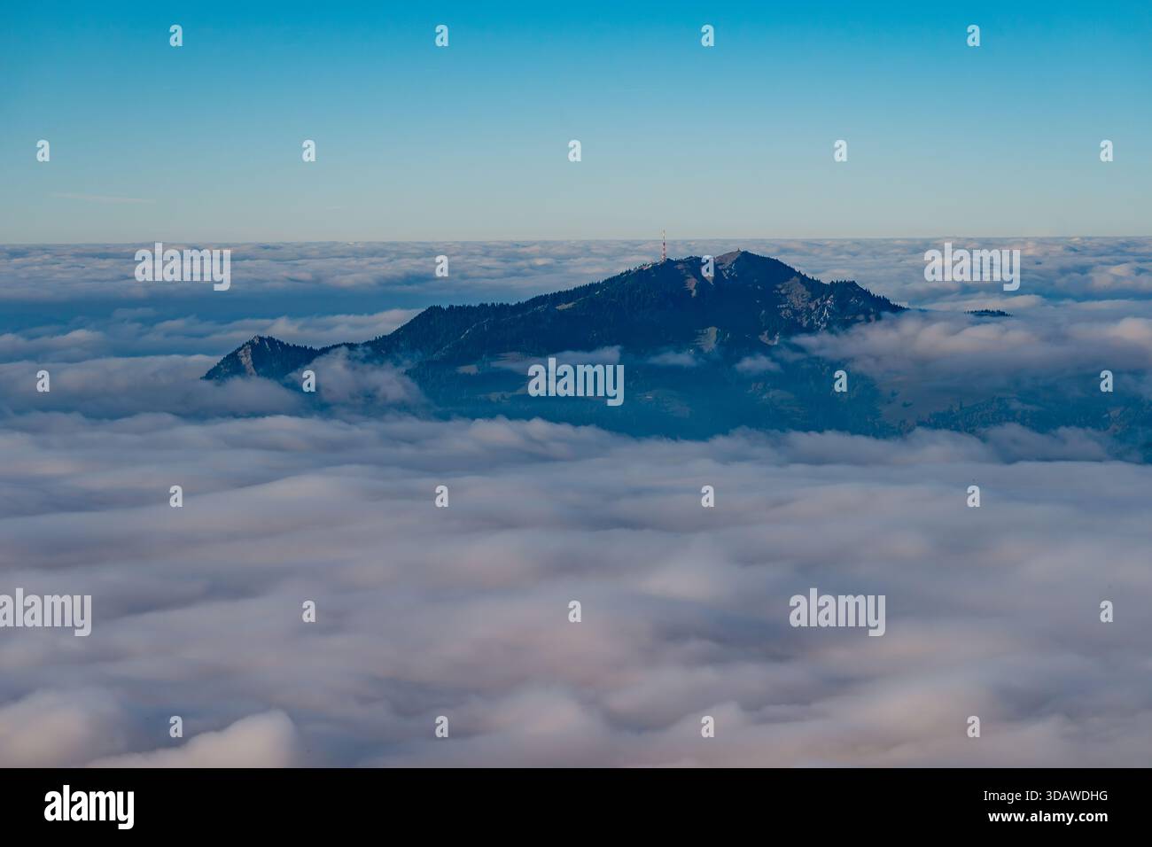Atemberaubende Aussicht auf einen Berggipfel aus der Luft, der über einem ausgedehnten Wolkenmeer auftaucht und in den Allgäuer Alpen Ruhe und Ehrfurcht weckt Stockfoto