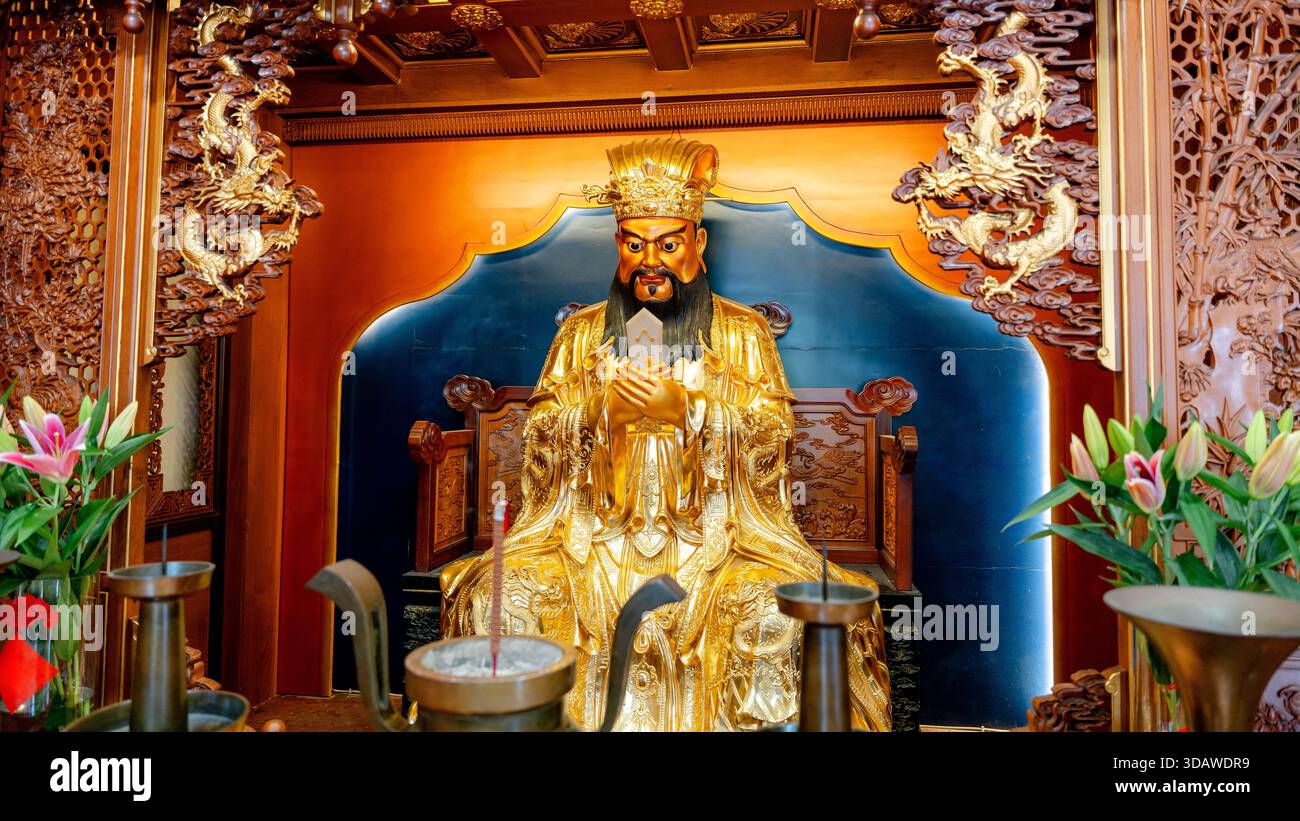 Eine goldene Gottheit-Statue mit komplizierten Drachenschnitzereien und Blumenmotiven in einem traditionellen Shanghai Tempel, die exquisite Handwerkskunst zeigt Stockfoto
