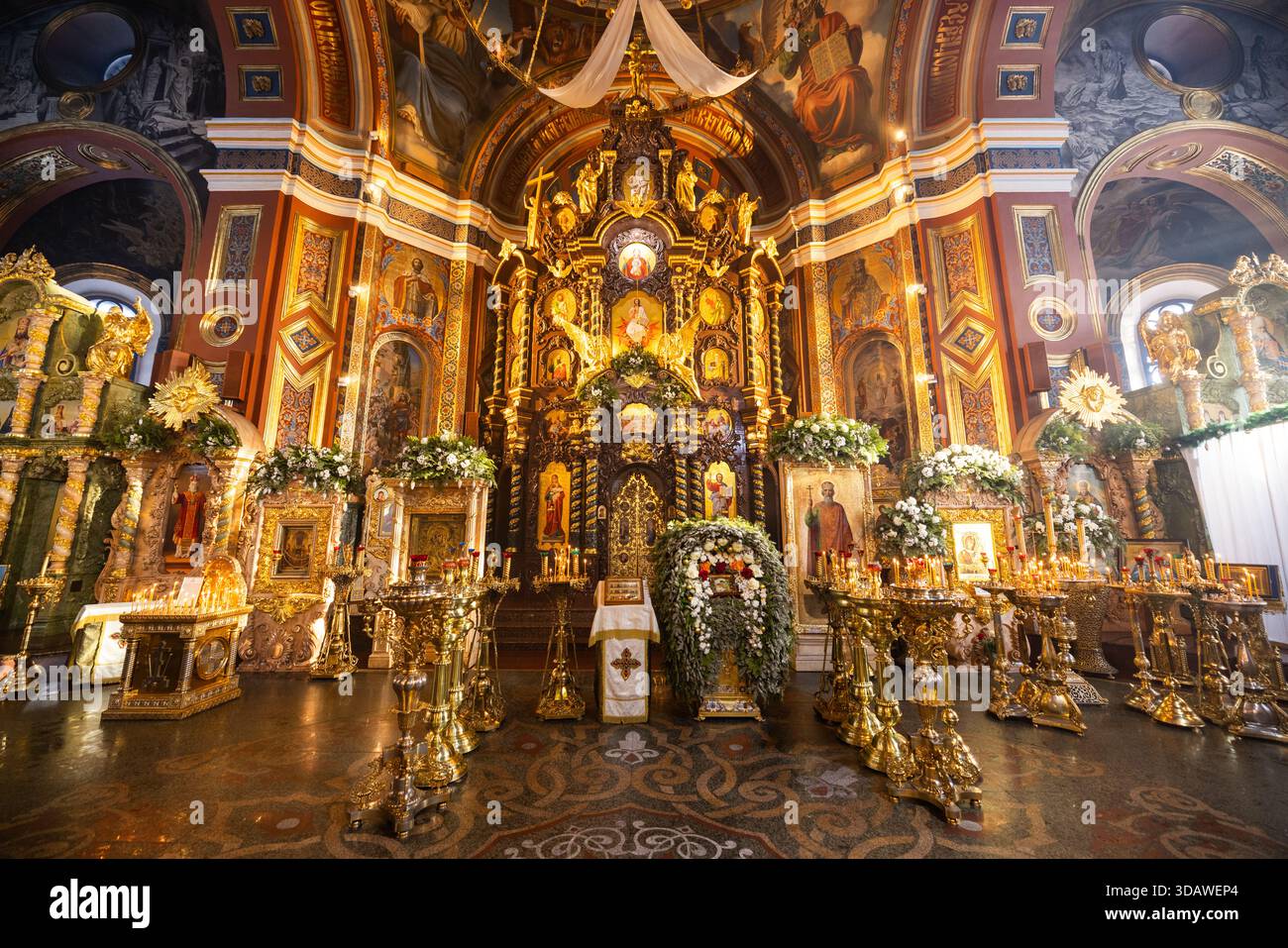 Blick auf kunstvoll verzierte Goldverzierungen im Kontrast zu den farbenfrohen religiösen Kunstwerken in einer Kathedrale, die spirituelle Hingabe widerspiegelt, Irkutsk, Irkutskaja obl Stockfoto