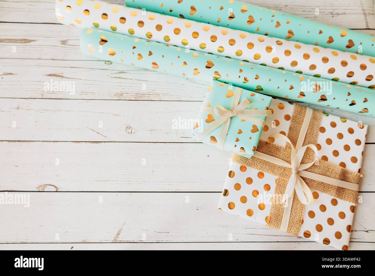 Stilvolle Geschenkverpackungsszene mit Papierrollen und verzierten Schachteln auf modernem strukturiertem Hintergrund. Flache Ladefläche für Heimwerkerprojekte, festliche Aktionen und Meer Stockfoto