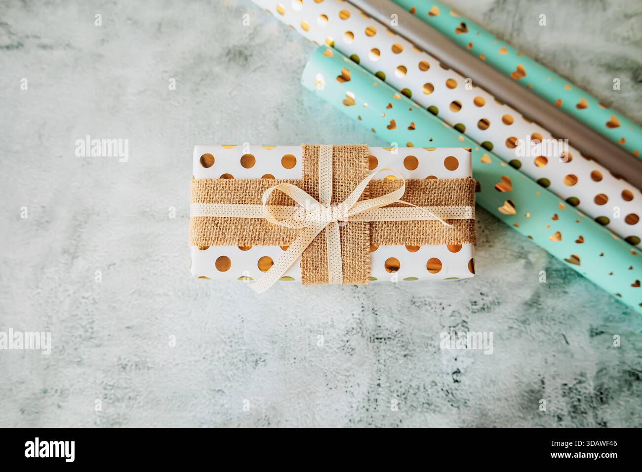 Stilvolle Geschenkverpackungsszene mit Papierrollen und verzierten Schachteln auf modernem strukturiertem Hintergrund. Flache Ladefläche für Heimwerkerprojekte, festliche Aktionen und Meer Stockfoto