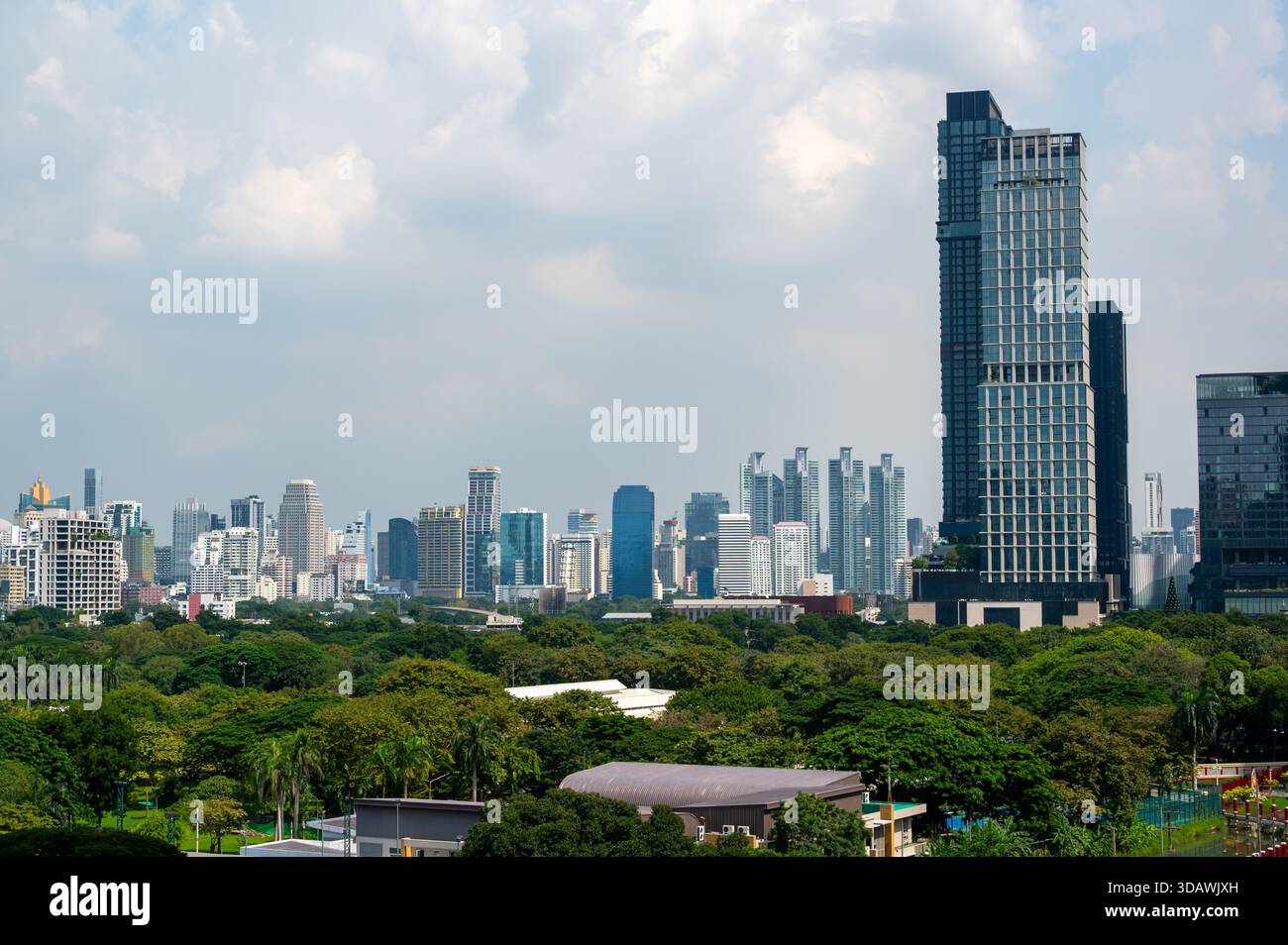 Panoramablick auf die weit entfernten Hochhäuser von Bangkok mit dem Lumphini Park im Vordergrund, der ruhige Grünflächen und eine breite Skyline der Stadt darunter kombiniert Stockfoto