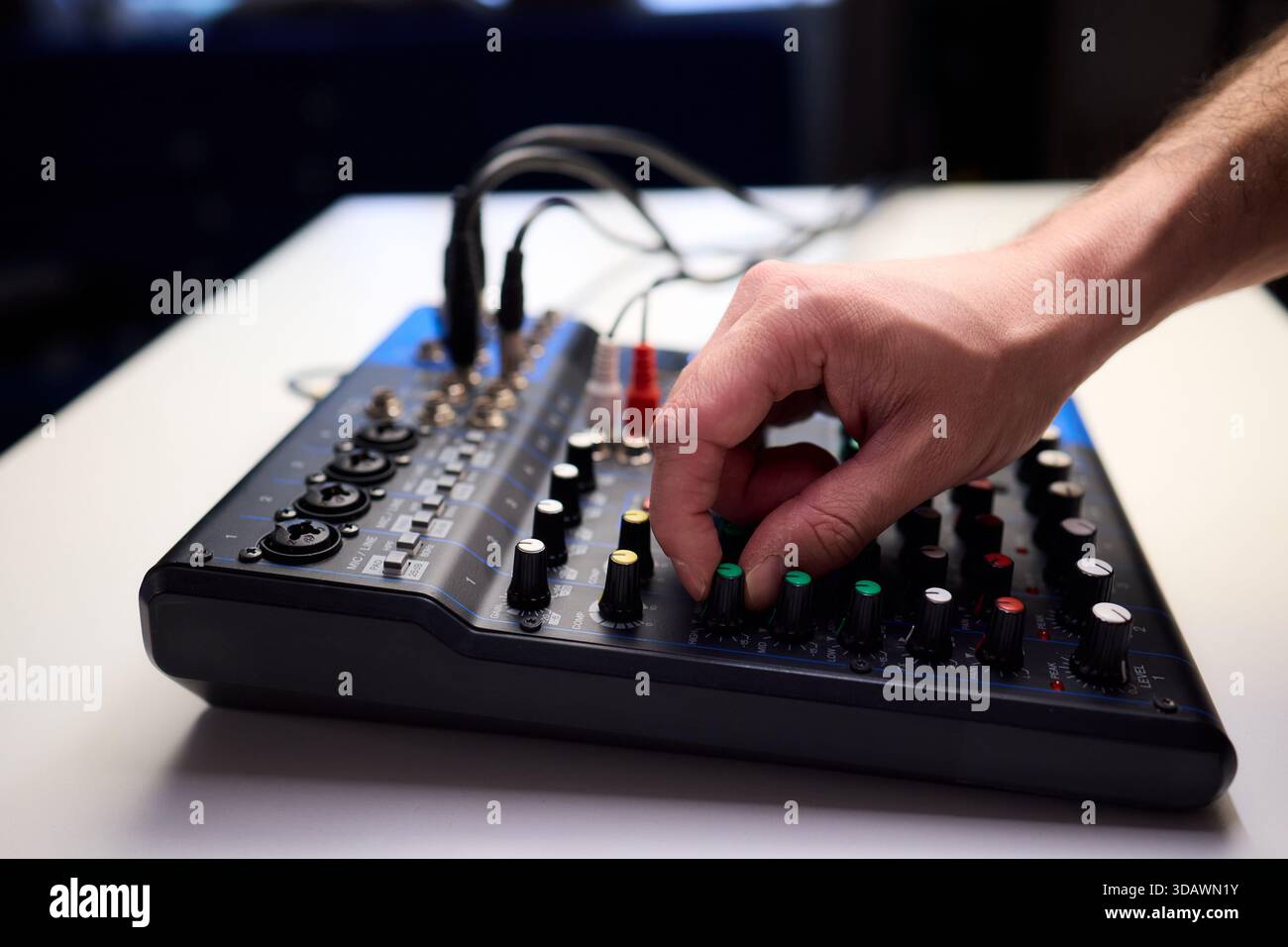 Tastfinger bedienen die beleuchteten Drehregler während der Soundcheck-Einrichtung, professionelle Techniker stellen die Soundausrüstung mit mehreren angeschlossenen Kabeln fertig Stockfoto