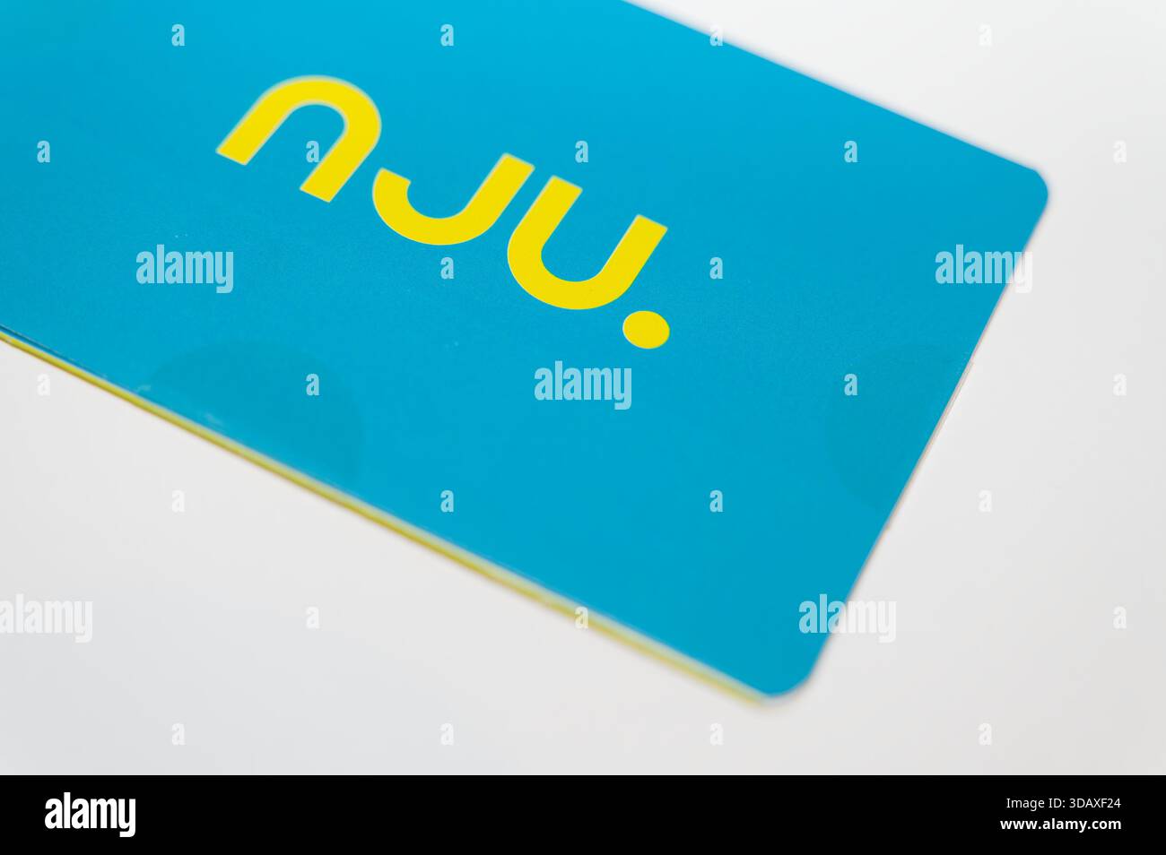 Blaues Nju-SIM-Kartenpaket mit markantem gelbem Logo, Nahaufnahme auf weißem Hintergrund. Stockfoto