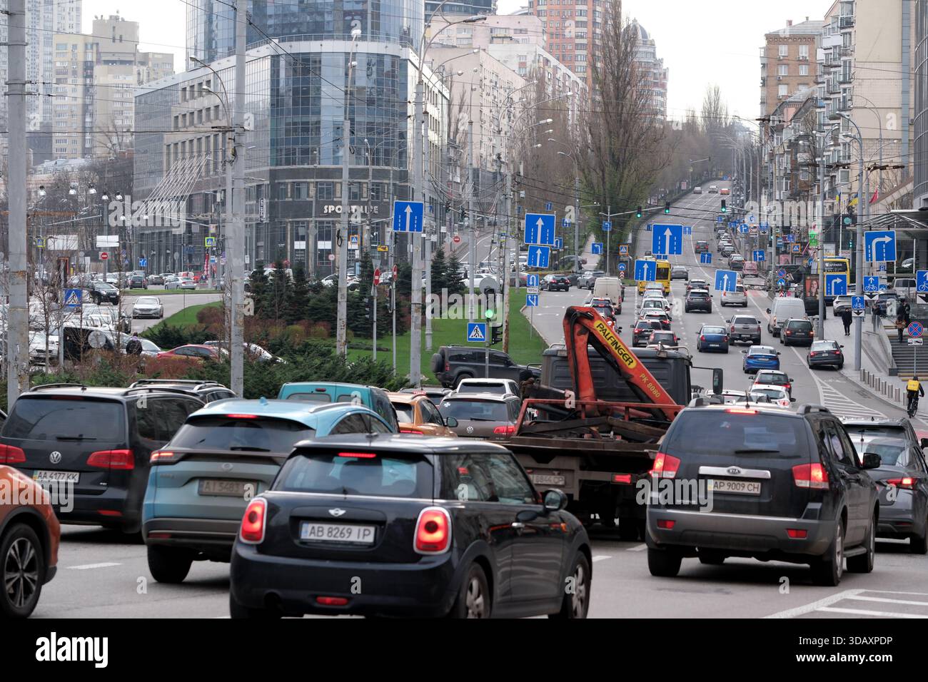An einem Wochentagnachmittag fahren Autos und Lastwagen durch eine geschäftige Stadtstraße. Kiew, Ukraine. Dezember 2025. Stockfoto