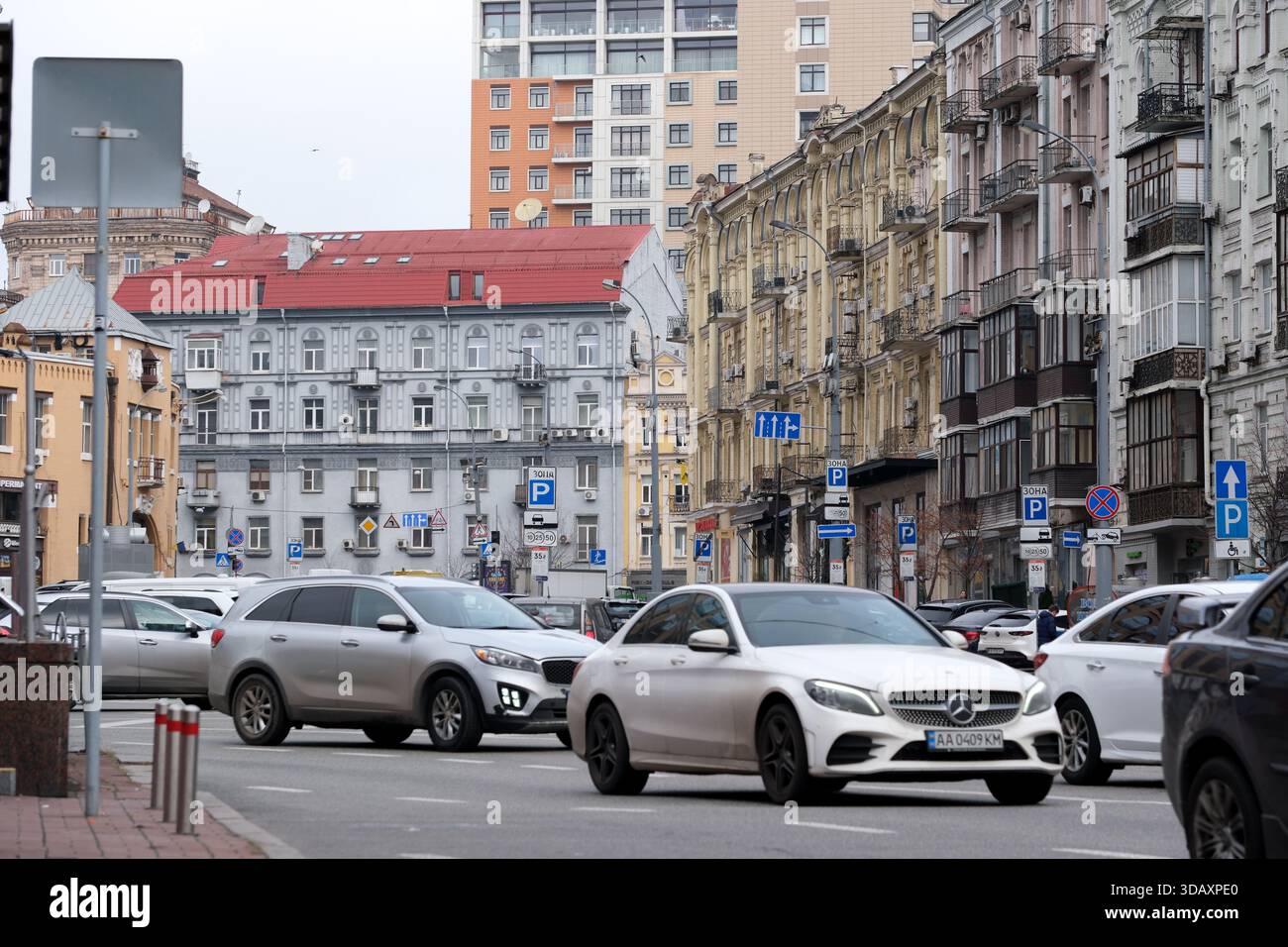 Der Verkehr fließt reibungslos vorbei an wunderschönen alten Gebäuden in einer pulsierenden Stadt. Kiew, Ukraine. Dezember 2025. Stockfoto