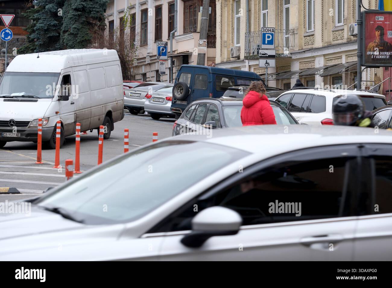Der Verkehr füllt die belebte Straße, während Fußgänger durch die Szene navigieren. Kiew, Ukraine. Dezember 2025. Stockfoto