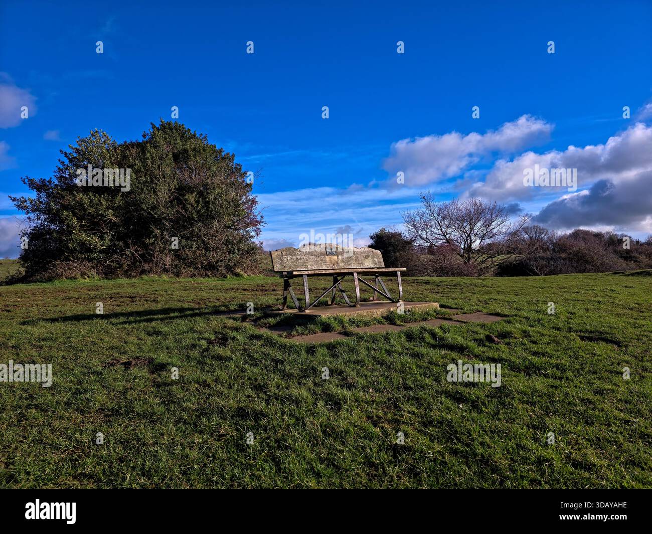 Einsame Holzbank auf Grashügel in friedlicher englischer Landschaft Stockfoto