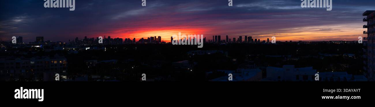 Extra breiter Panoramablick auf die Skyline der Innenstadt von Miami vor einem lebhaften bunten dunklen Sonnenuntergang Stockfoto