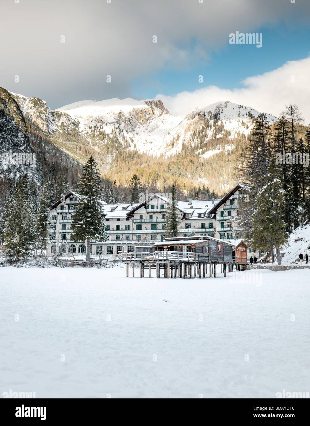 Hotel Lago di Prags im Winterschnee, mit dem gefrorenen See im Vordergrund und den dramatischen Berggipfeln der Dolomiten im Hintergrund, c Stockfoto
