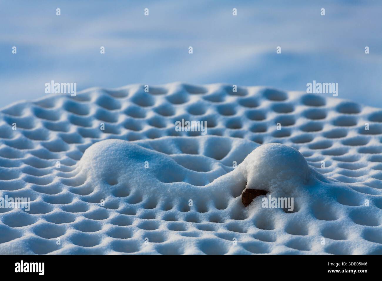 Ein Picknicktisch aus Metall mit frischem Schnee zeigt atemberaubende Muster, die die Schönheit der Natur mit der Ruhe des Winters in Ludington, Michigan, verbinden Stockfoto