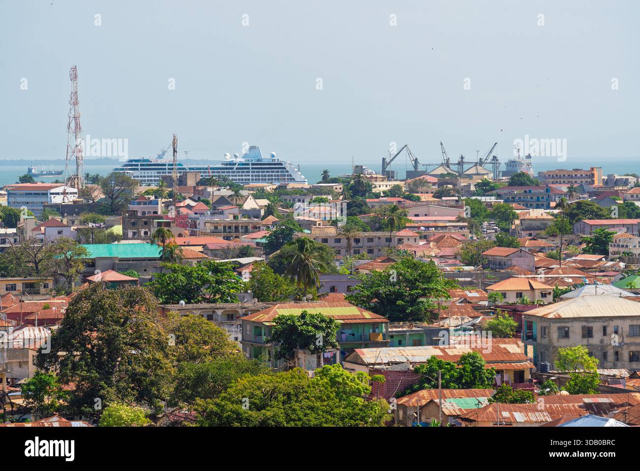Erhöhter Blick auf Banjul, Gambia, Wohndächer und ein großes Kreuzfahrtschiff, das in der Hafenstadt angedockt ist Stockfoto