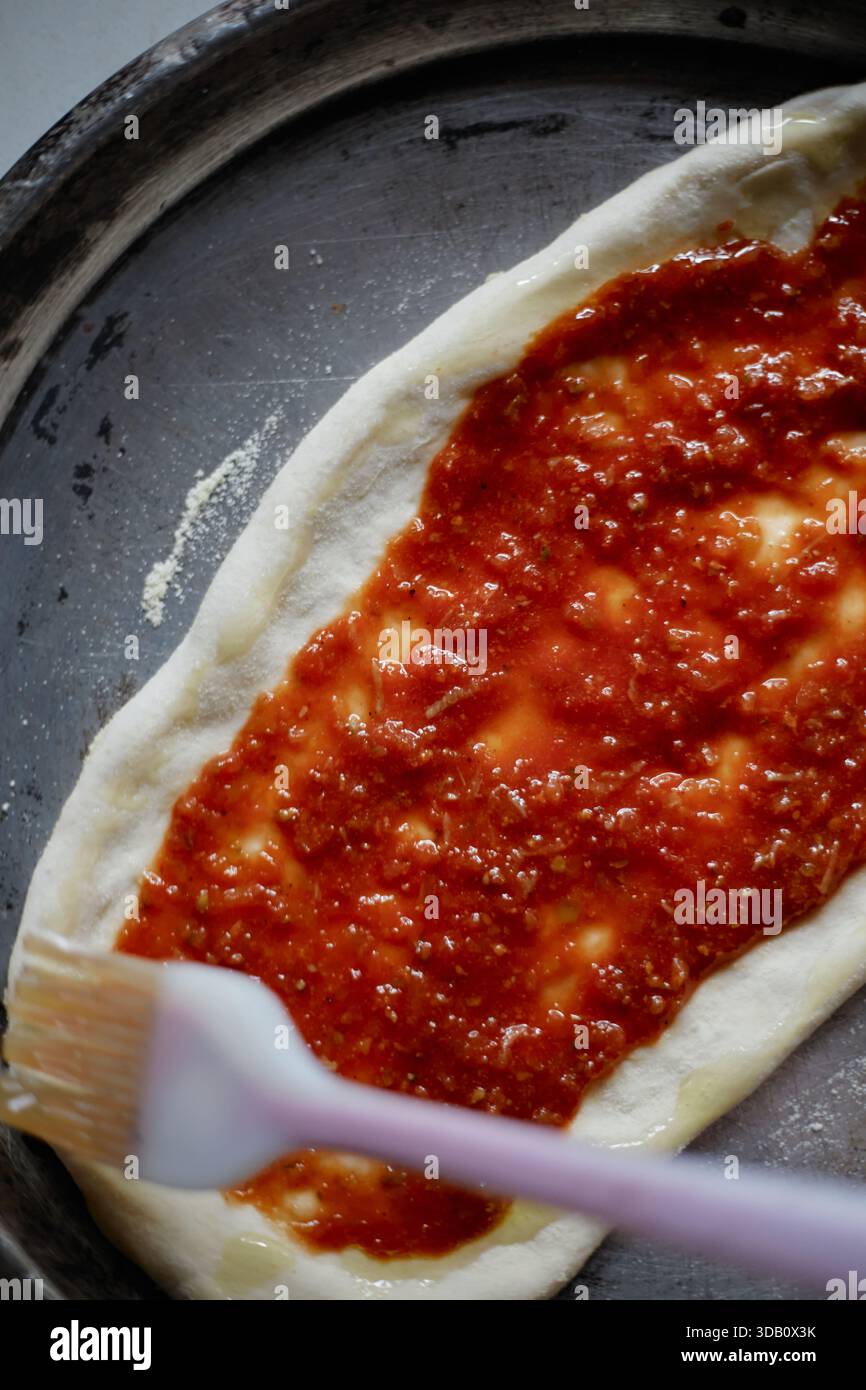 Tomatensauce auf Pizzapfanne verteilen, selektive Fokussierung Stockfoto