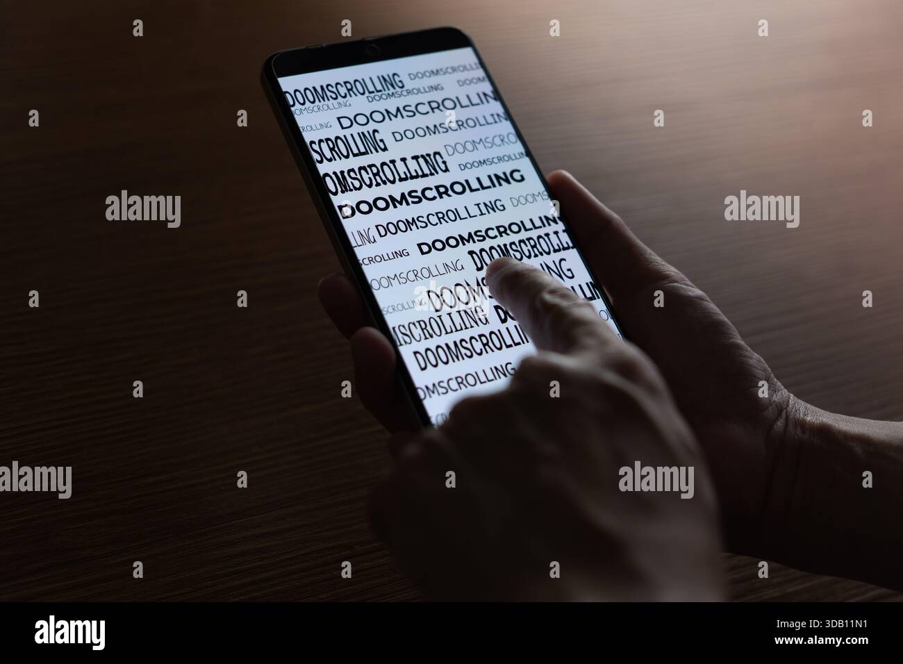 Nahaufnahme einer Person, die ein Smartphone verwendet, wobei das Wort „Doomscrolling“ auf dem Bildschirm wiederholt wird. Digitale sucht, negativer Nachrichtenkonsum Stockfoto
