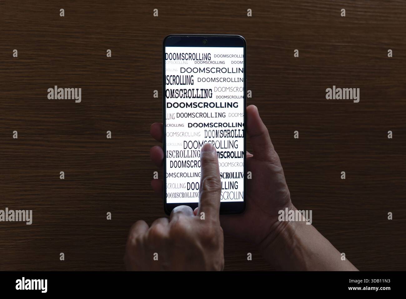 Nahaufnahme einer Person, die ein Smartphone verwendet, wobei das Wort „Doomscrolling“ auf dem Bildschirm wiederholt wird. Digitale sucht, negativer Nachrichtenkonsum Stockfoto