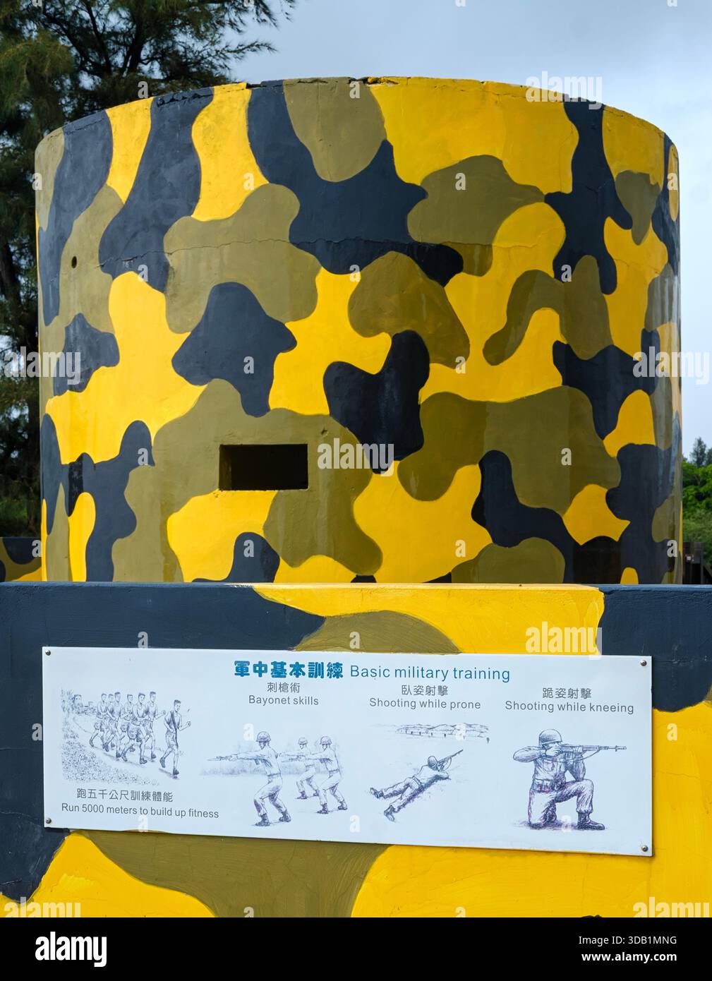 Ein bunt bemalter gelb-schwarzer Tarnbunker in Kinmen, Taiwan, mit einem pädagogischen Schild, das grundlegende militärische Trainingsübungen beschreibt Stockfoto