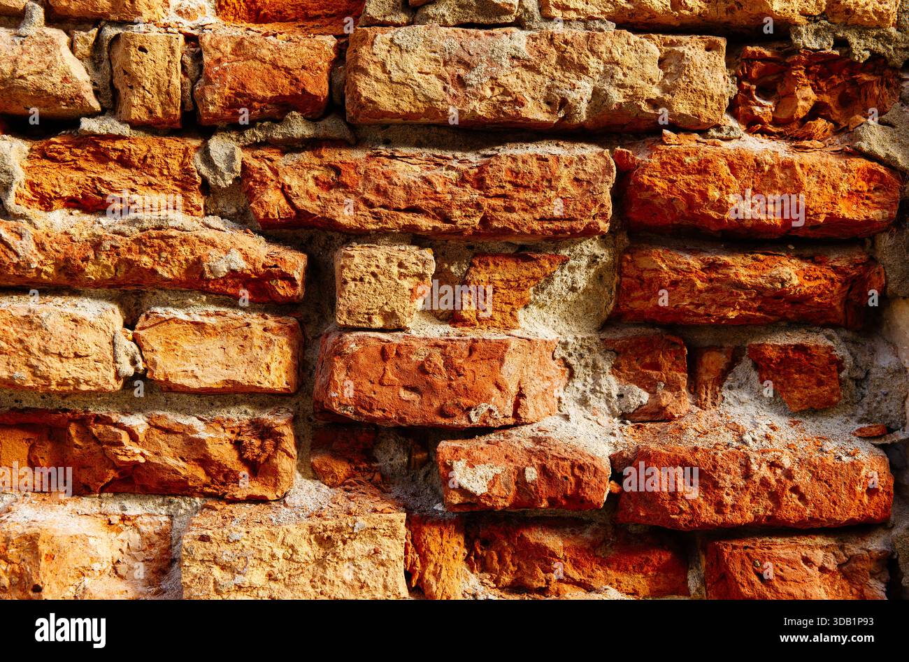Verwitterte rote Ziegelwand mit rustikaler Textur und natürlichen Mustern. Stockfoto