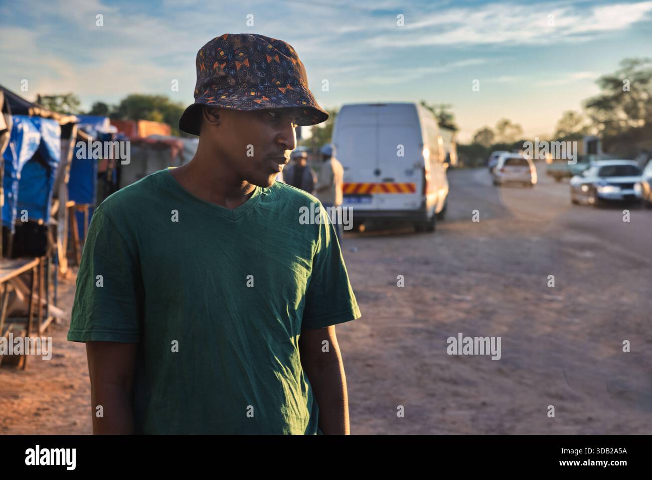 Einzelne junge afrikanische Männer in der Altstadt am Bahnhofshandel bei Sonnenaufgang, Johannesburg Stadt, Südafrika, Freizeitkleidung, Straße mit Autos Stockfoto