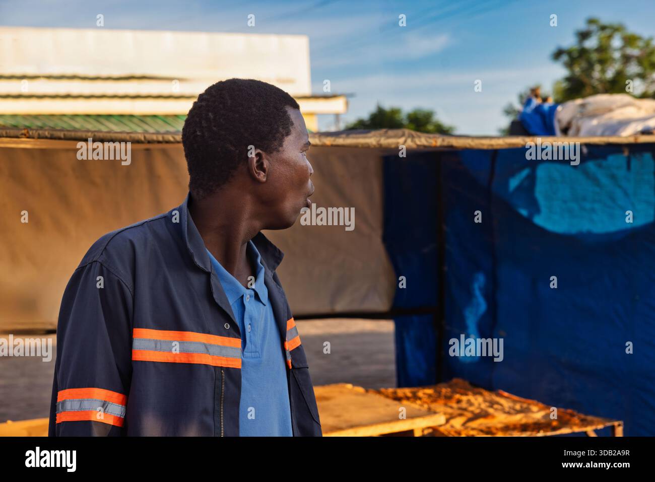 Einzelne afrikanische Männer in der Altstadt am Bahnhofszentrum bei Sonnenaufgang, Johannesburg City, Südafrika, Arbeitskleidung mit orangefarbenem reflektierendem Streifen Stockfoto