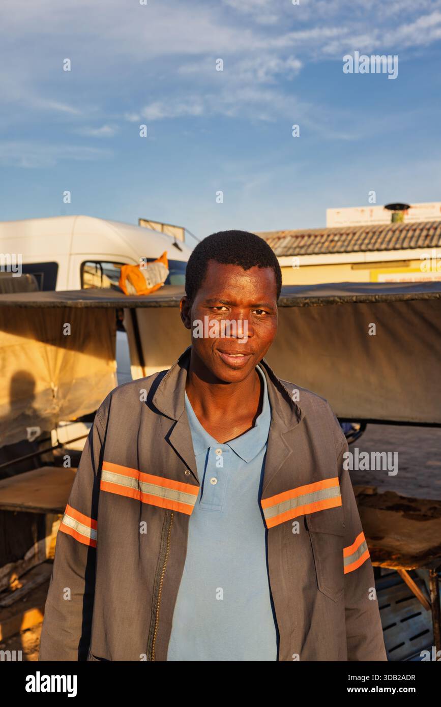 Einzelne afrikanische Männer in der Altstadt am Bahnhofszentrum bei Sonnenaufgang, Johannesburg City, Südafrika, Arbeitskleidung mit orangefarbenem reflektierendem Streifen Stockfoto