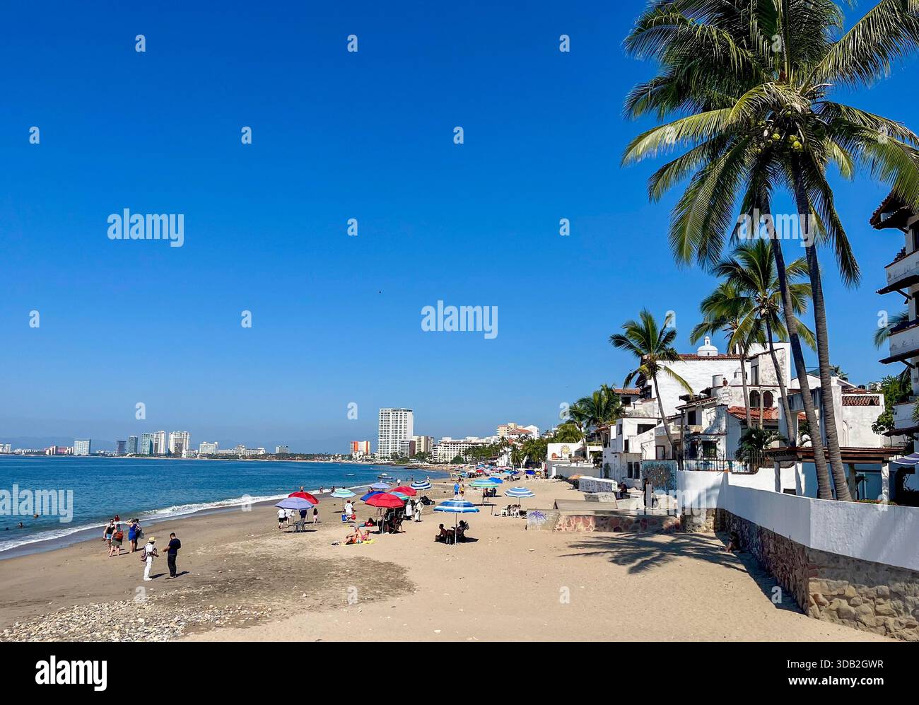 Die Menschen entspannen sich und schlendern entlang des Strandes in Puerto Vallarta, Mexiko, und genießen die Pazifikküste, das warme Wetter und die lebhafte Atmosphäre am Meer. Stockfoto