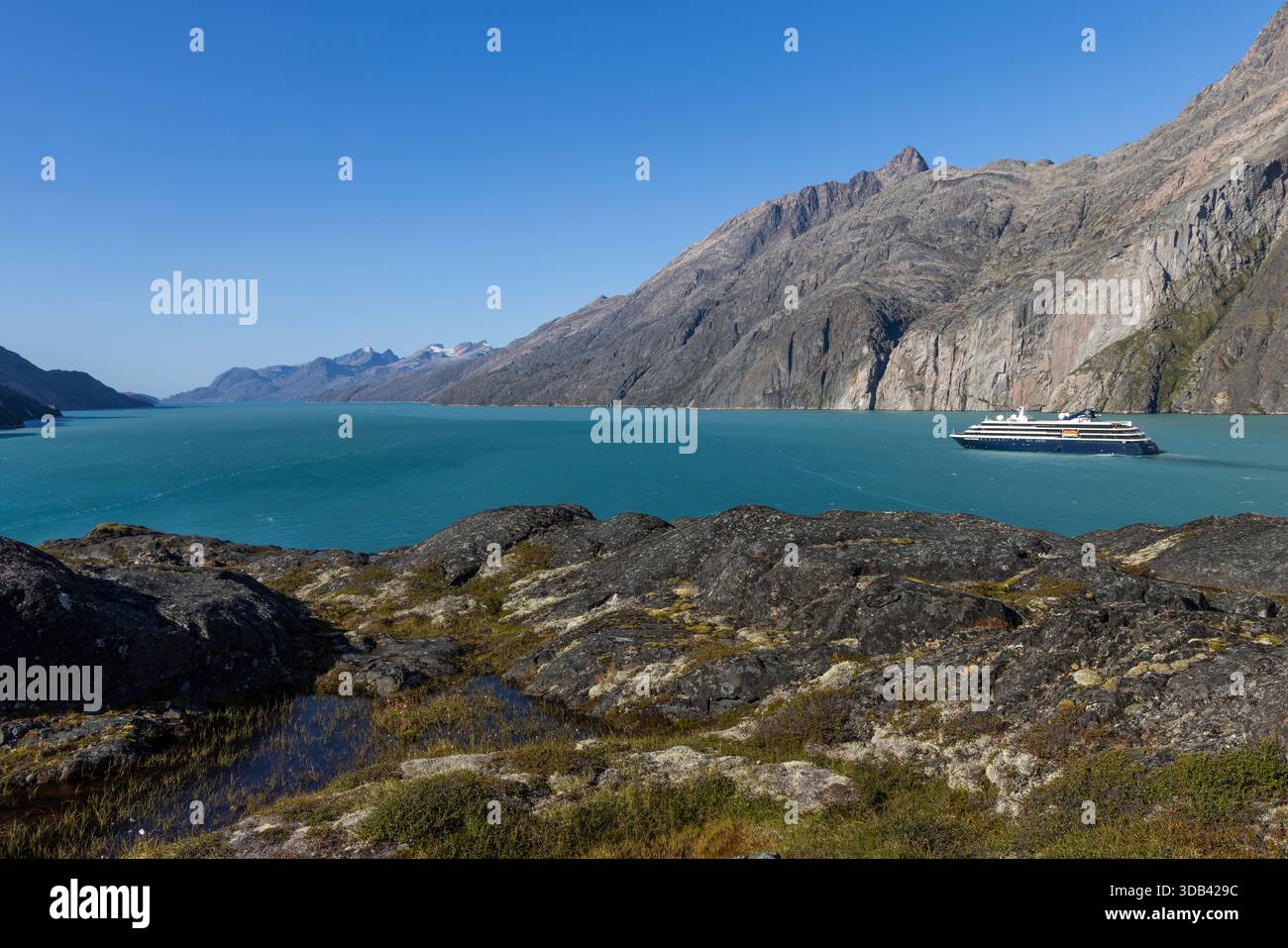 Expeditionskreuzschiff World Voyager (Atlas Ocean Voyages) mit Felsen im Vordergrund und Bergen dahinter, Sermillinnguaq Fjord, Queqatta, Greenlan Stockfoto