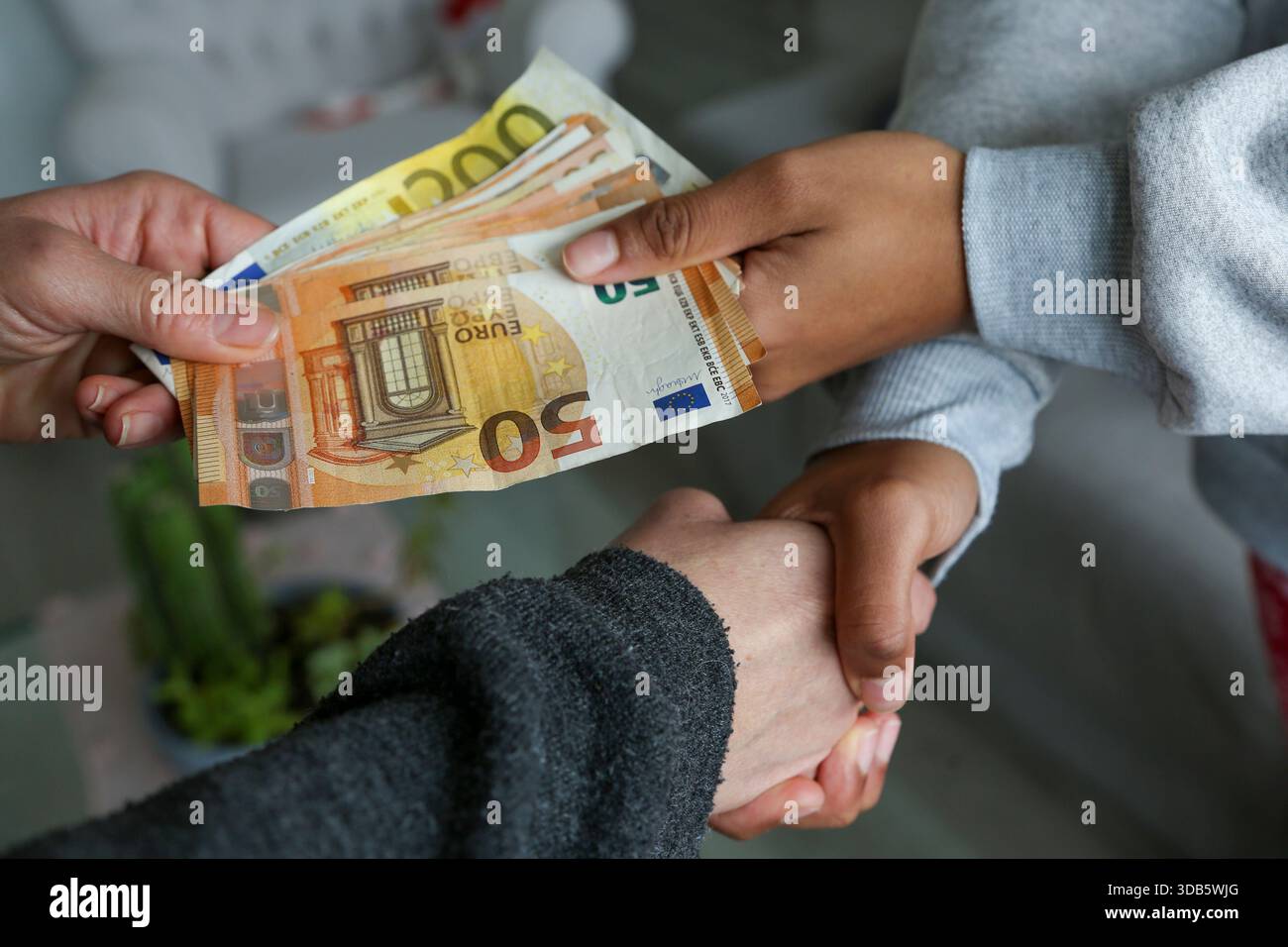 Zwei Frauen schließen einen Deal ab, überreichen Geld und schütteln die Hände; eine mit heller afroamerikanischer Haut und die andere Kaukasierin. Korruption Stockfoto