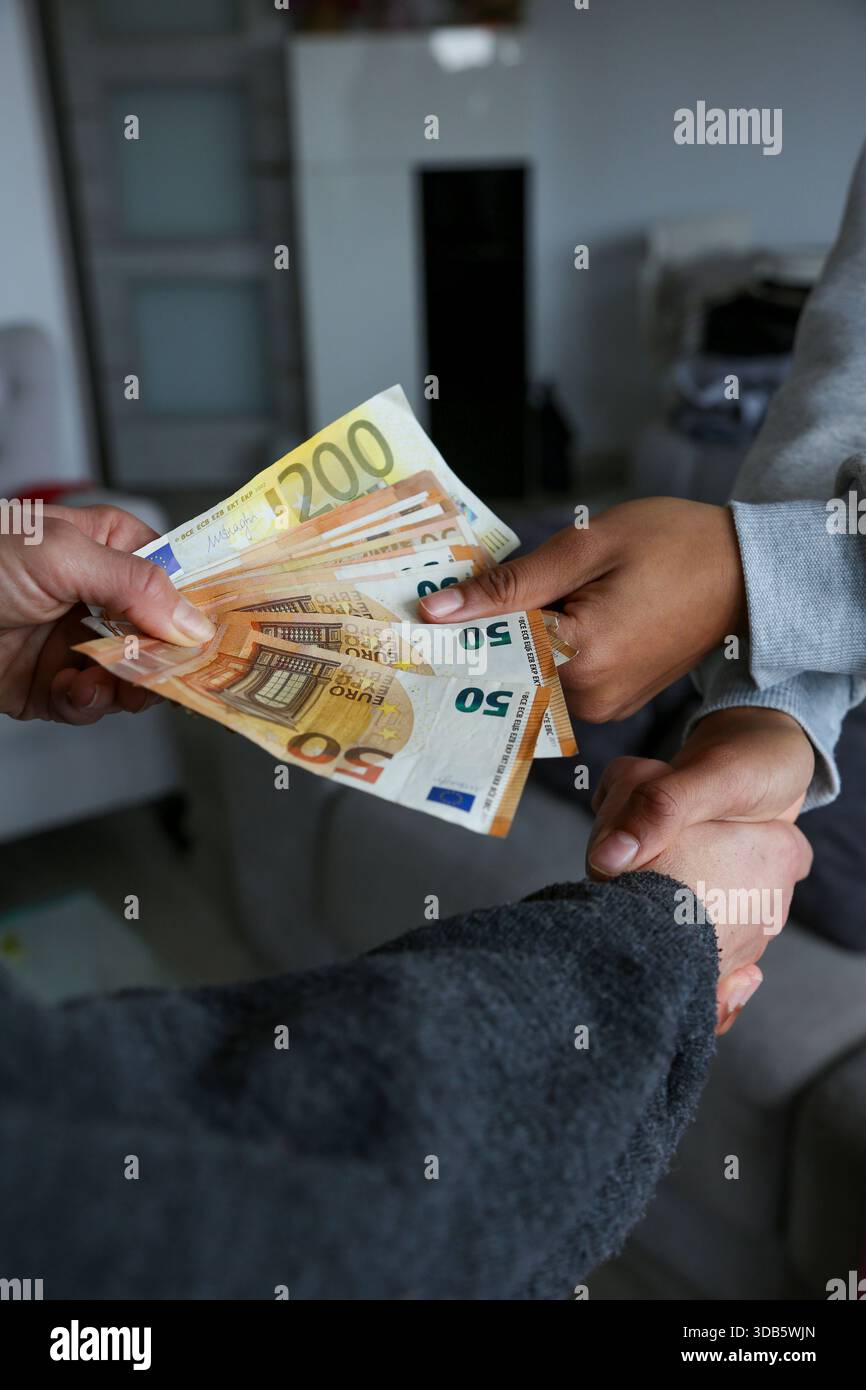 Zwei Frauen schließen einen Deal ab, überreichen Geld und schütteln die Hände; eine mit heller afroamerikanischer Haut und die andere Kaukasierin. Korruption Stockfoto