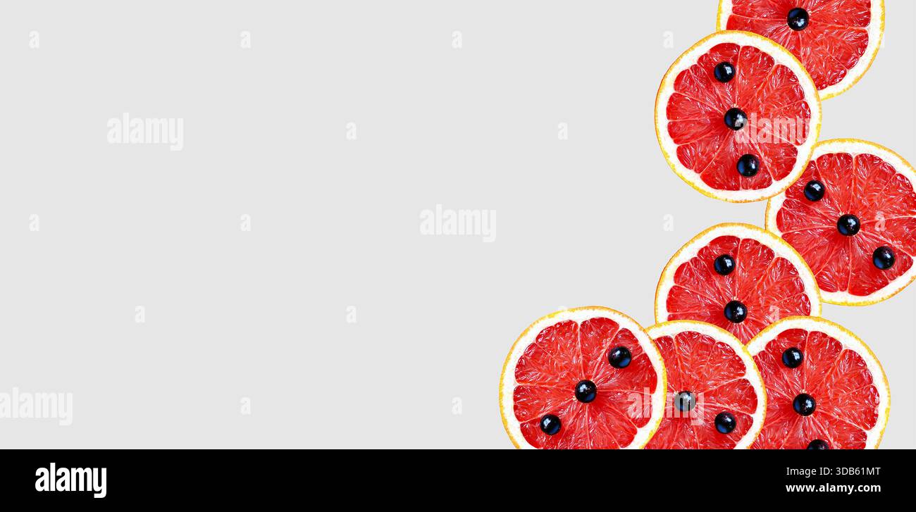 In Scheiben geschnittenes Hintergrundbild ​​grapefruit. Grapefruit mit schwarzen Johannisbeerbeeren. Zitrusscheiben, isoliert, künstlerische moderne Kunst, abstrakte Nahrung, gesunde Ernährung Stockfoto