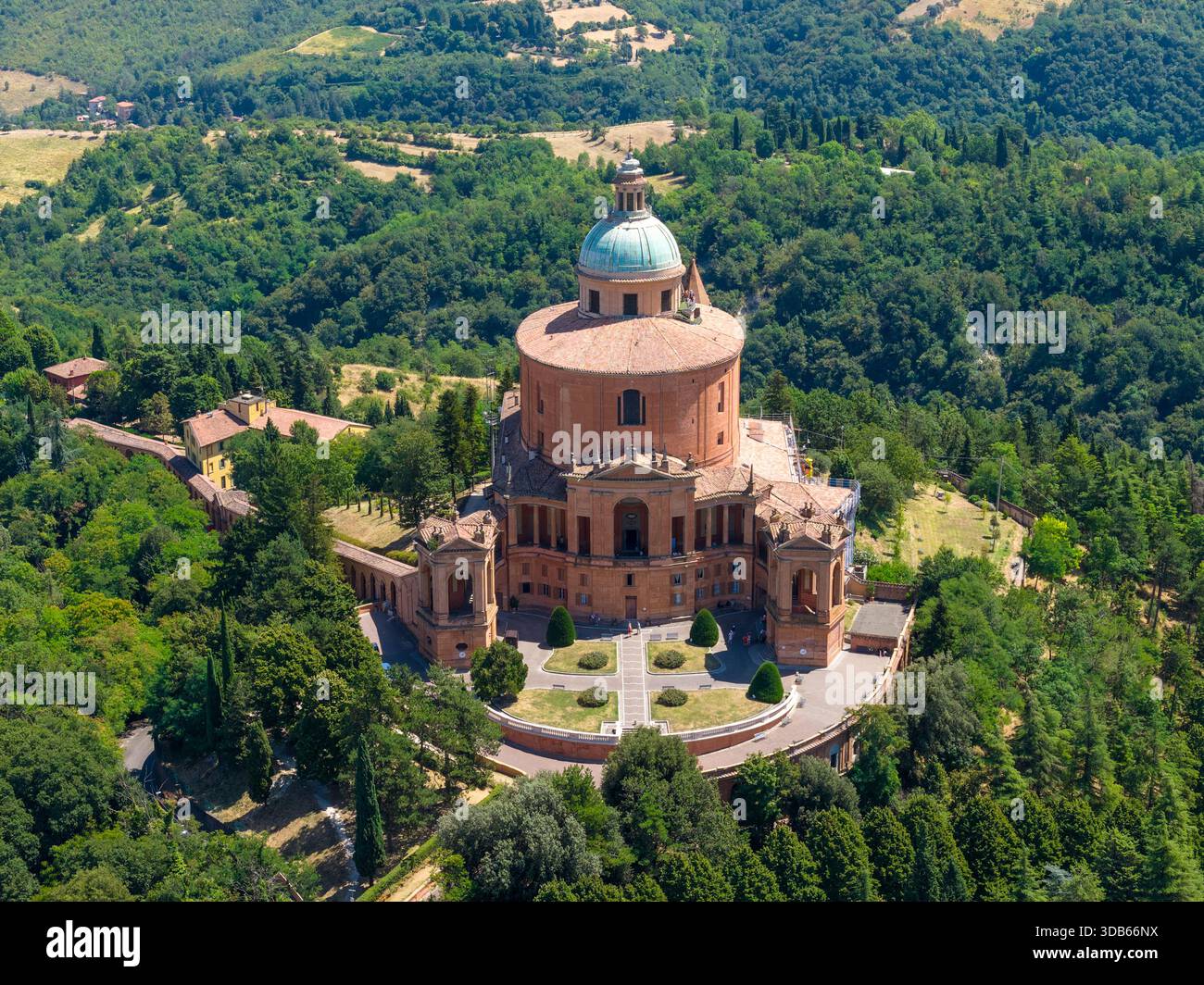 Blick aus der Vogelperspektive auf das barocke Heiligtum unserer Lieben Frau von San Luca auf dem Monte della Guardia, umgeben von bewaldeten Hügeln in der Nähe von Bologna Stockfoto