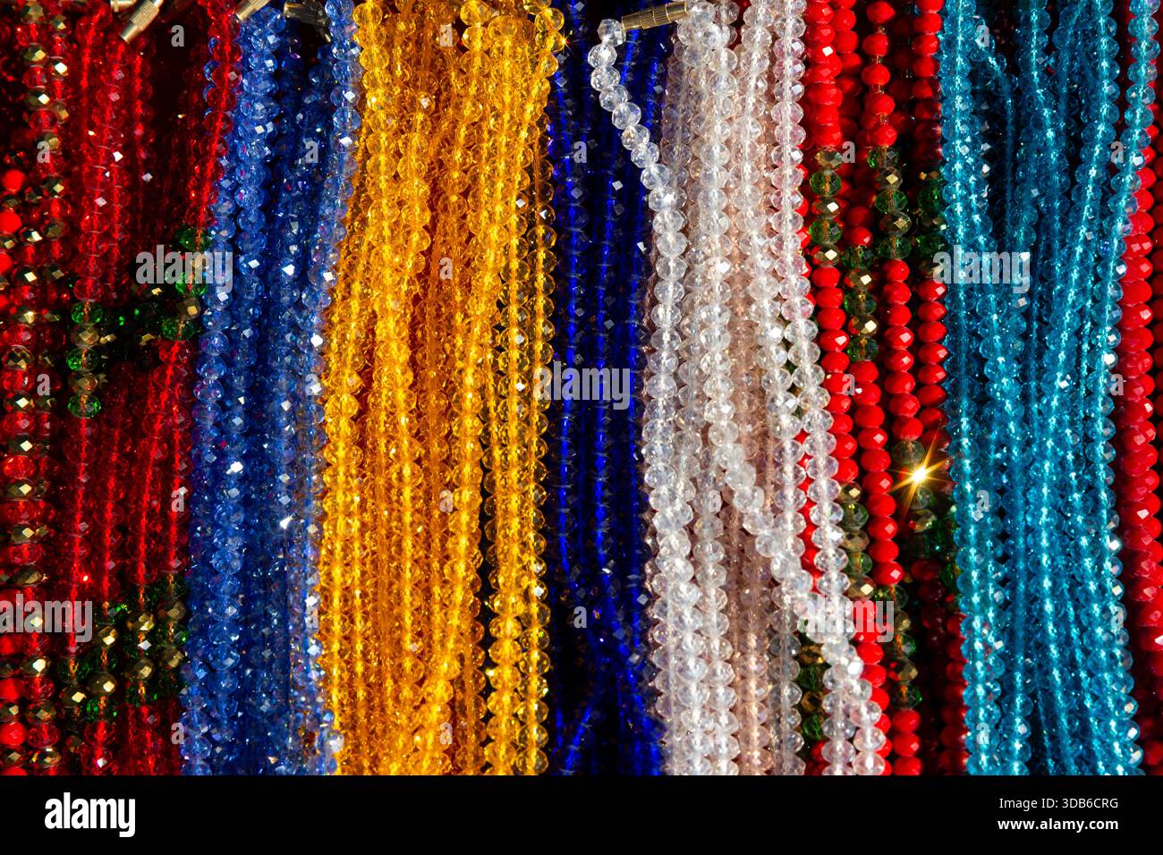Farbenfrohe vertikale Stränge handgemachter Glasperlen, die auf einem traditionellen Markt in Nepal ausgestellt werden. Stockfoto