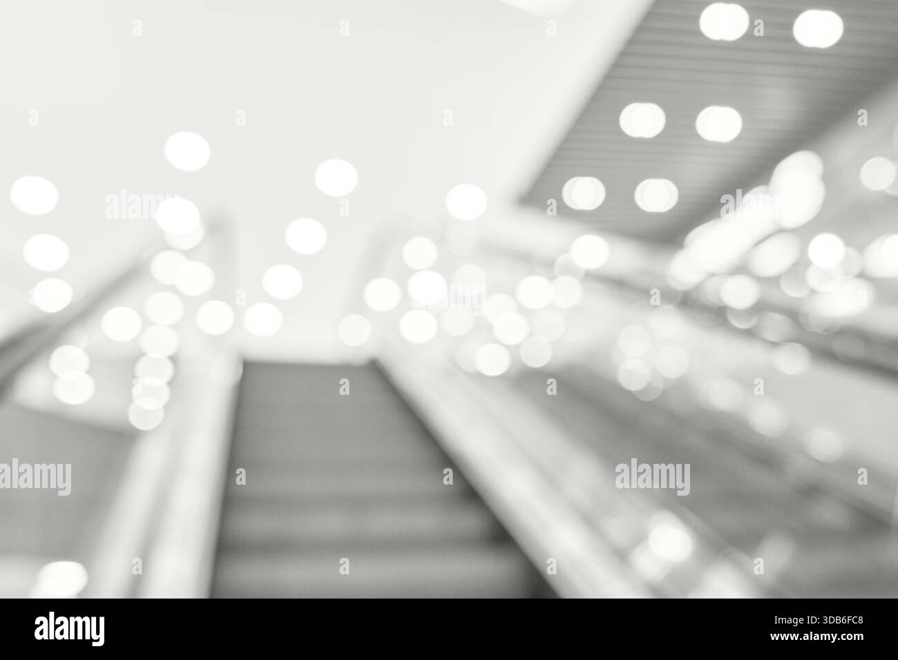 Abstraktes verschwommenes Bild einer Rolltreppe mit hellen Bokeh-Lichtern in einem modernen Einkaufszentrum. Stockfoto