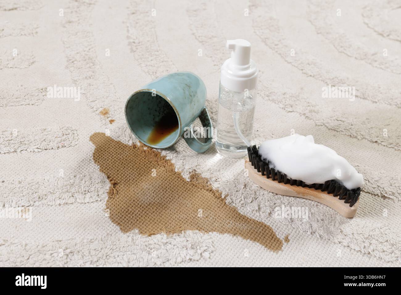 Kaffeegetränk auf weichem Teppich mit Reinigungsschaumbürste und durchsichtiger Spenderflasche für professionelle Fleckenbehandlung zu Hause Stockfoto