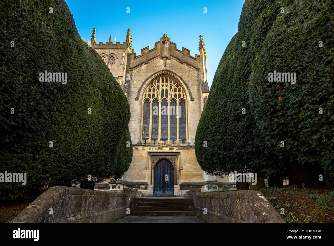 Historische Steinkirche mit großem Bogenfenster, flankiert von gepflegten Eiben und von Steintreppen in einem formellen Garten in St. Mary's Calne begrenzt Stockfoto