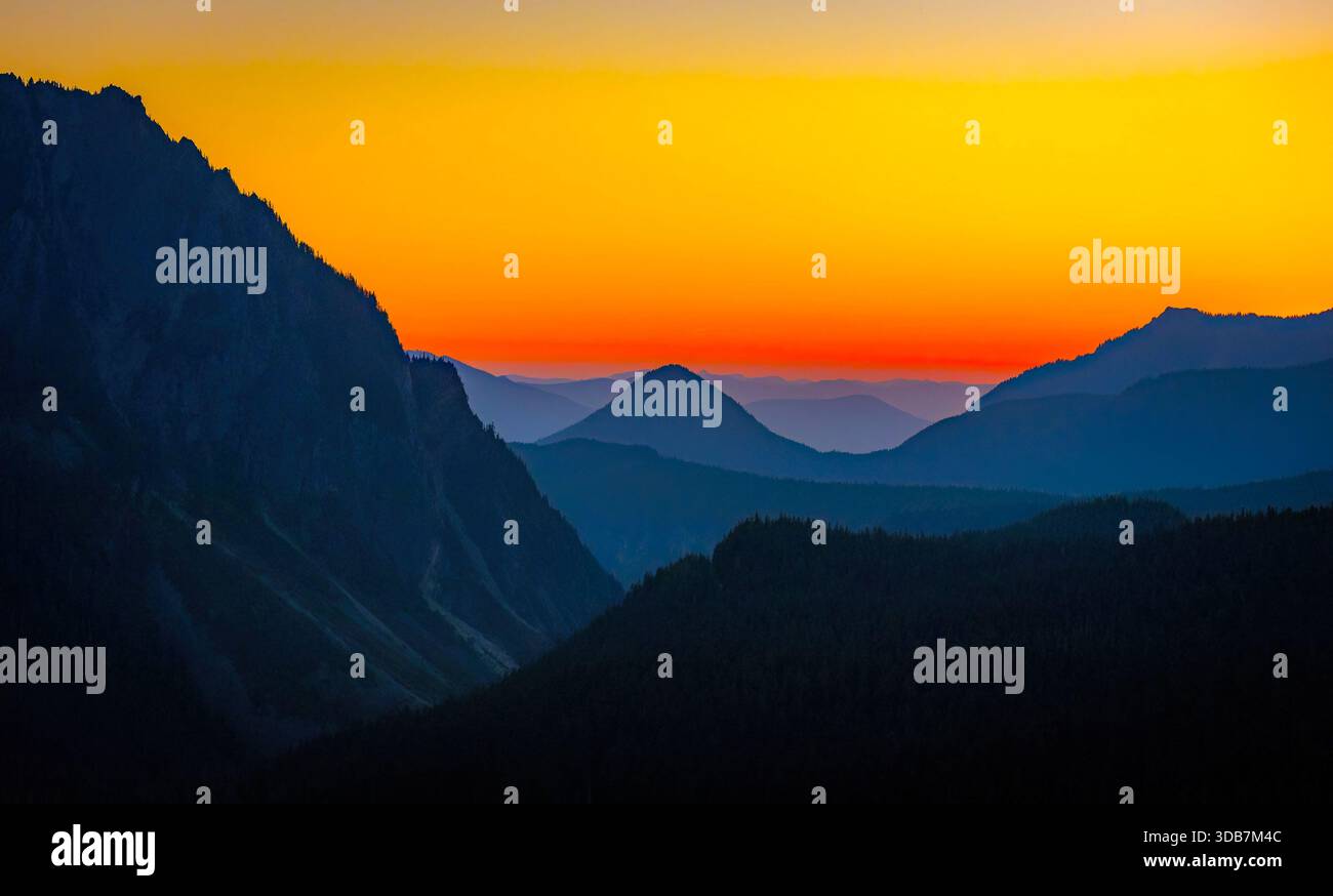 Ein farbenfroher Sonnenuntergang bietet einen herrlichen Blick auf den Mazama Ridge und den fernen Mount Adams, von Mount Rainiers Inspirationspunkt aus gesehen. Stockfoto